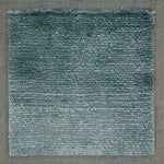 Handloomed rug with tonal border and raised cut pile shag field in soft teal.