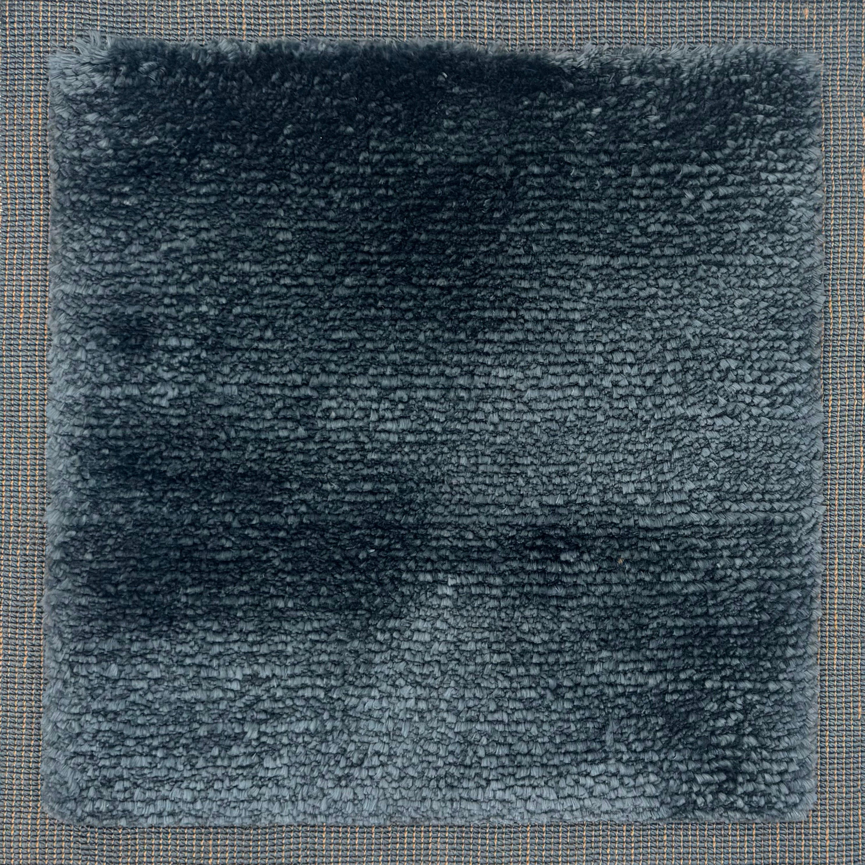 Handloomed rug with tonall border and raised cut pile shag field in dark blue.