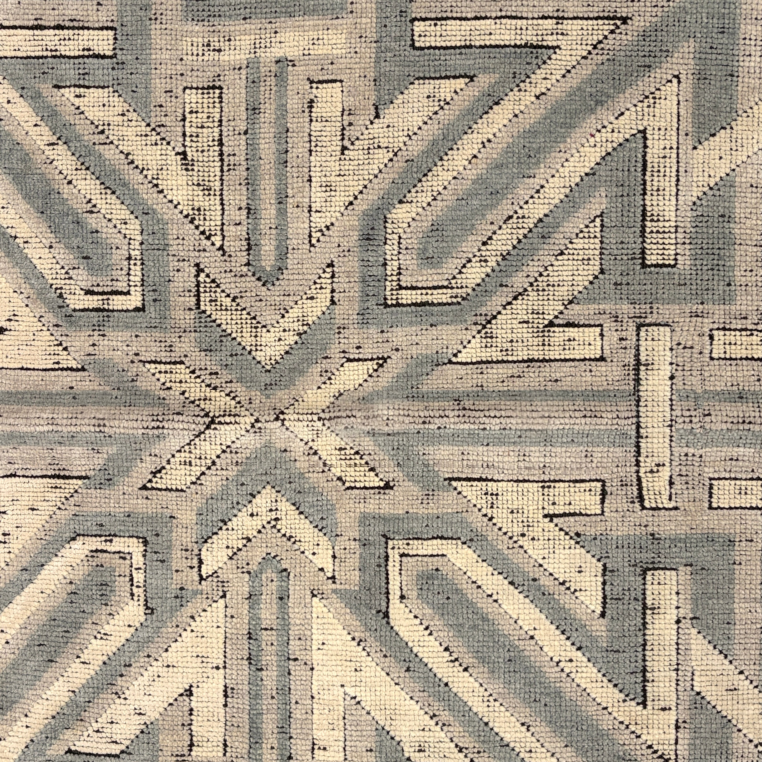 Geometric patterned rug with arrows in gray and beige tones