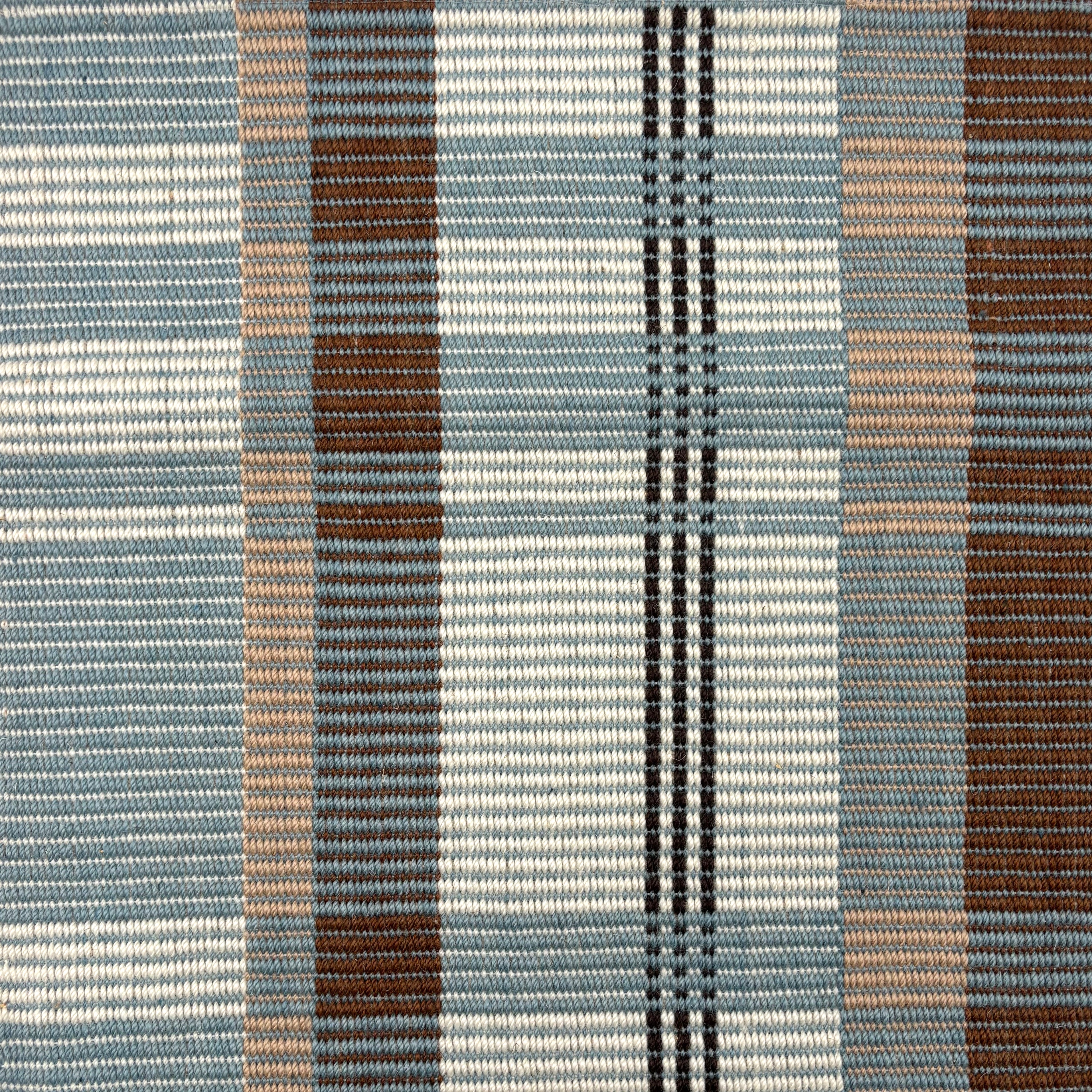 Handwoven rug in a large scale plaid in shades of teal, brown, tan, cream and black. 