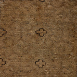 Handwoven rug with small black cross outlines on a brown field. 