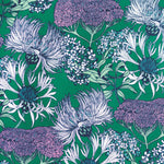Detail of wallpaper in a dense floral print in shades of cream, purple and green on a green field.