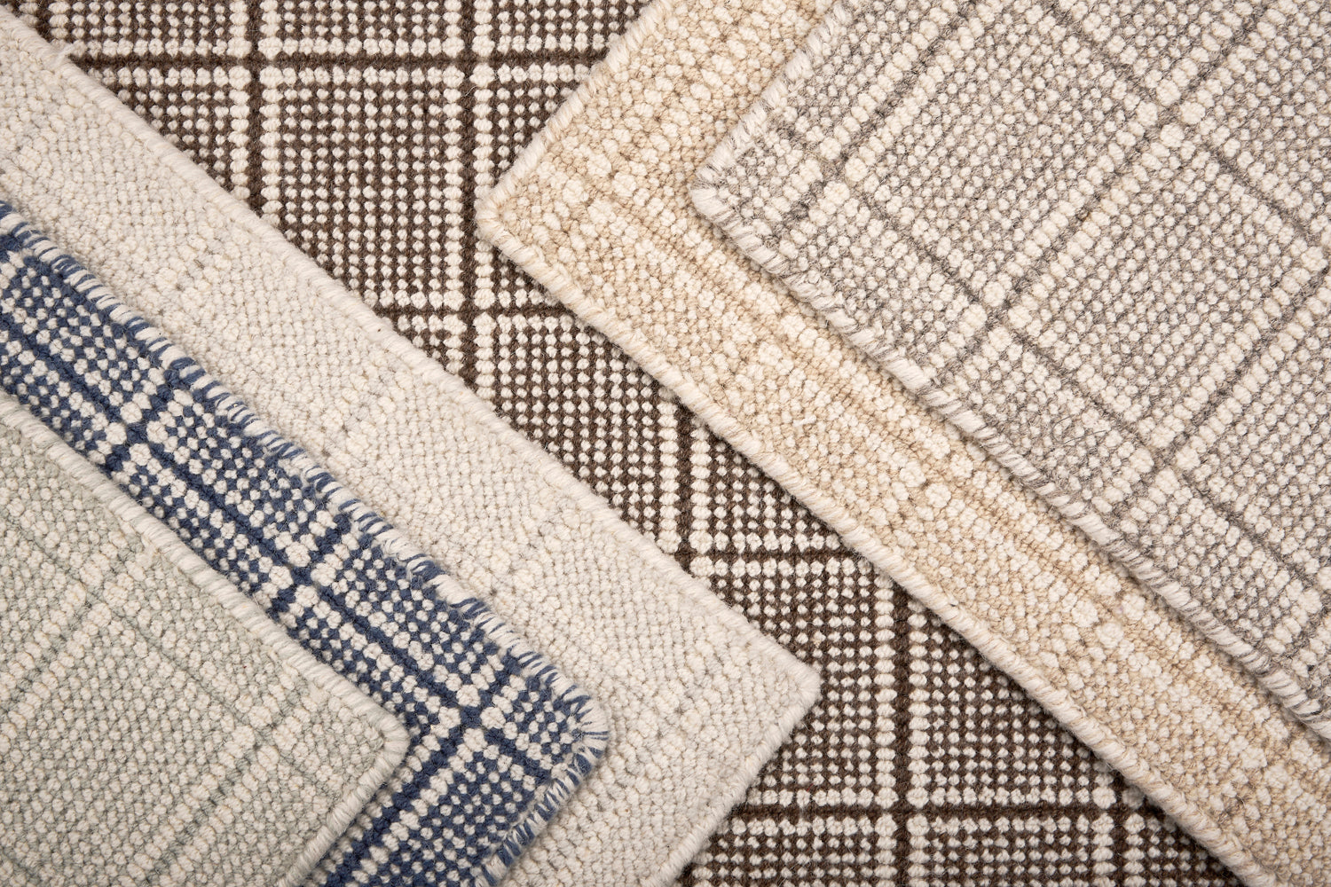 Close-up of various textured rug samples with plaid pattern in neutral colors.