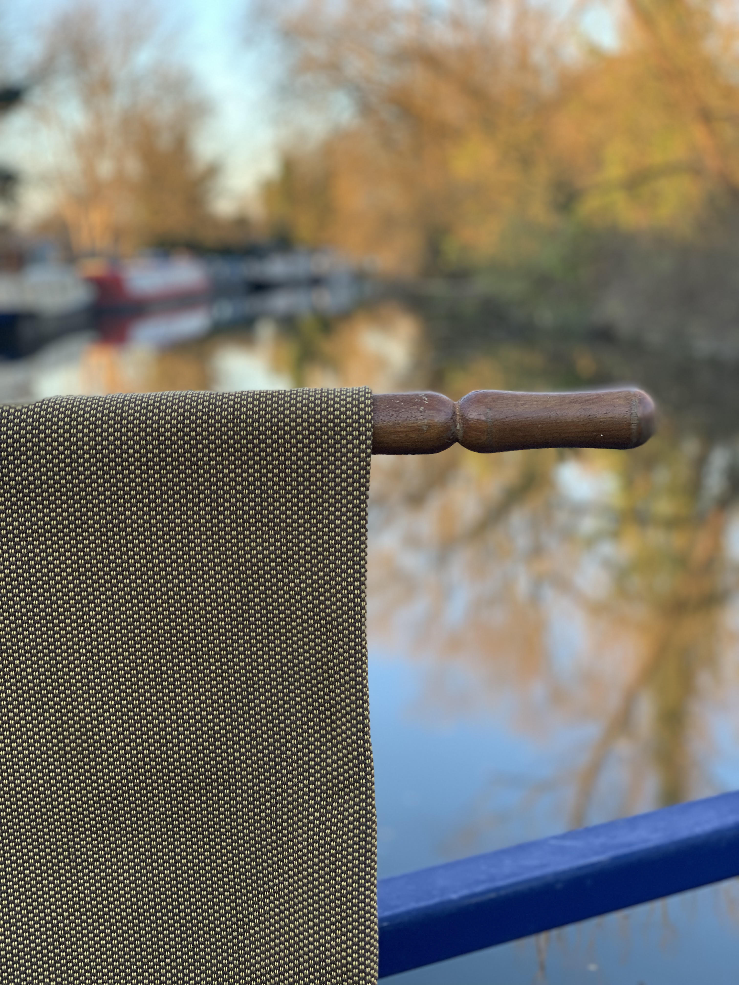 Close-up of a textured fabric with a wooden handle against a blurred natural background