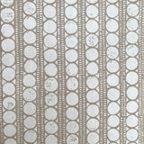Detail of wallpaper in a circle and stripe print in white on a oatmeal field.