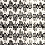 Detail of wallpaper in a playful hamsa hand print in black and brown on a cream field.