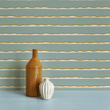 Two vases stand in front of a wall papered in an undulating stripe pattern in gold, white and blue-gray.