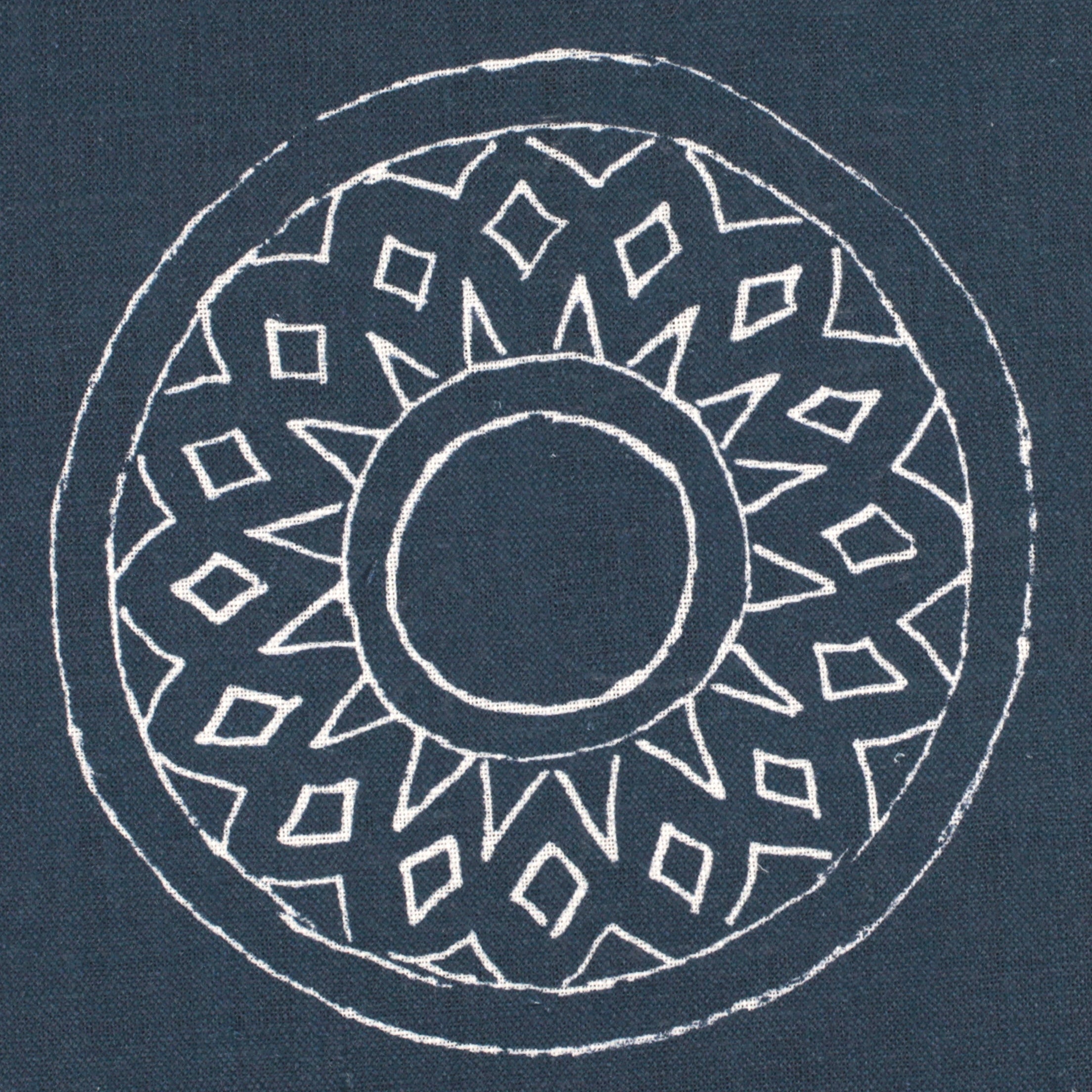 Detail of fabric in a repeating circular geometric print in white on a navy field.
