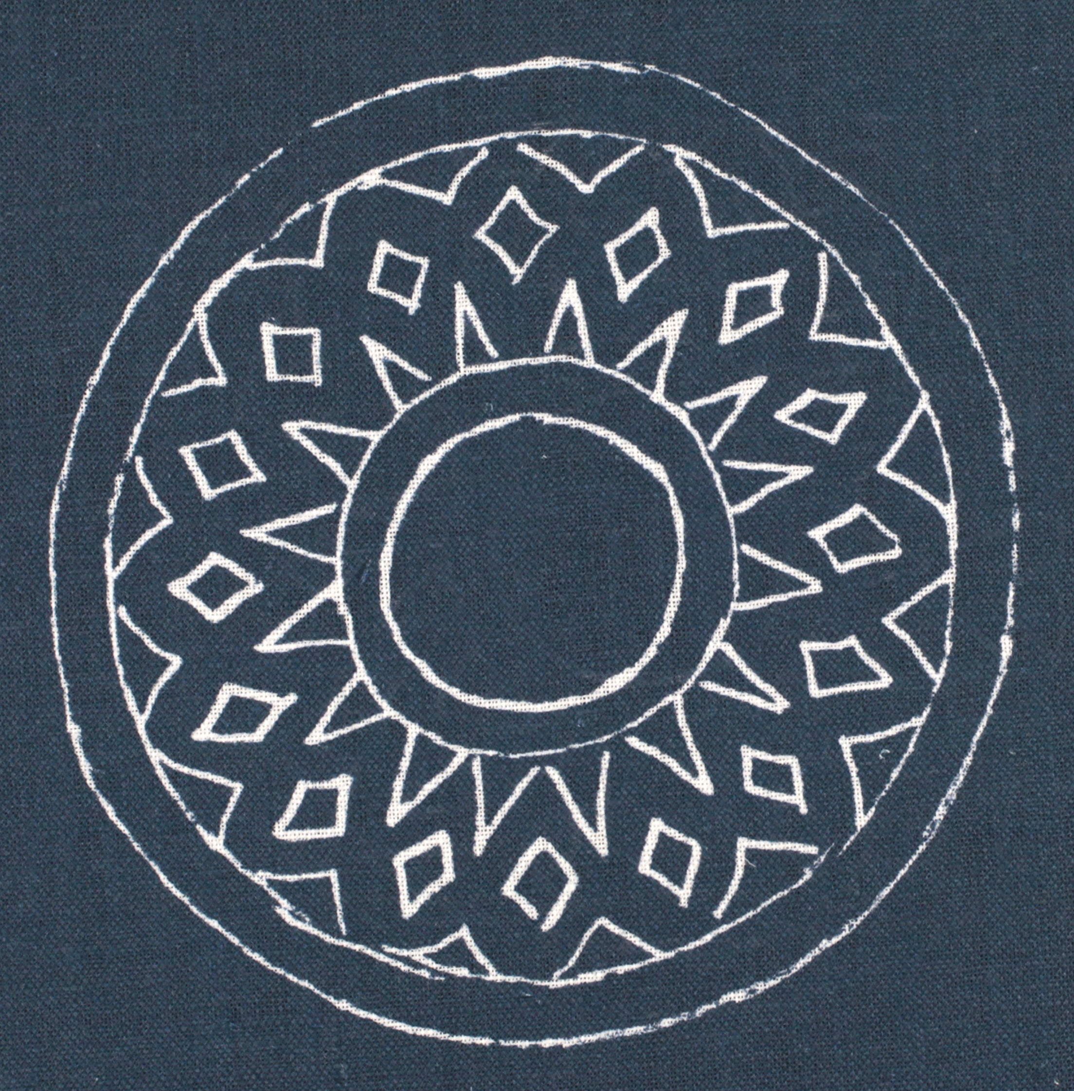 Detail of fabric in a repeating circular geometric print in white on a navy field.