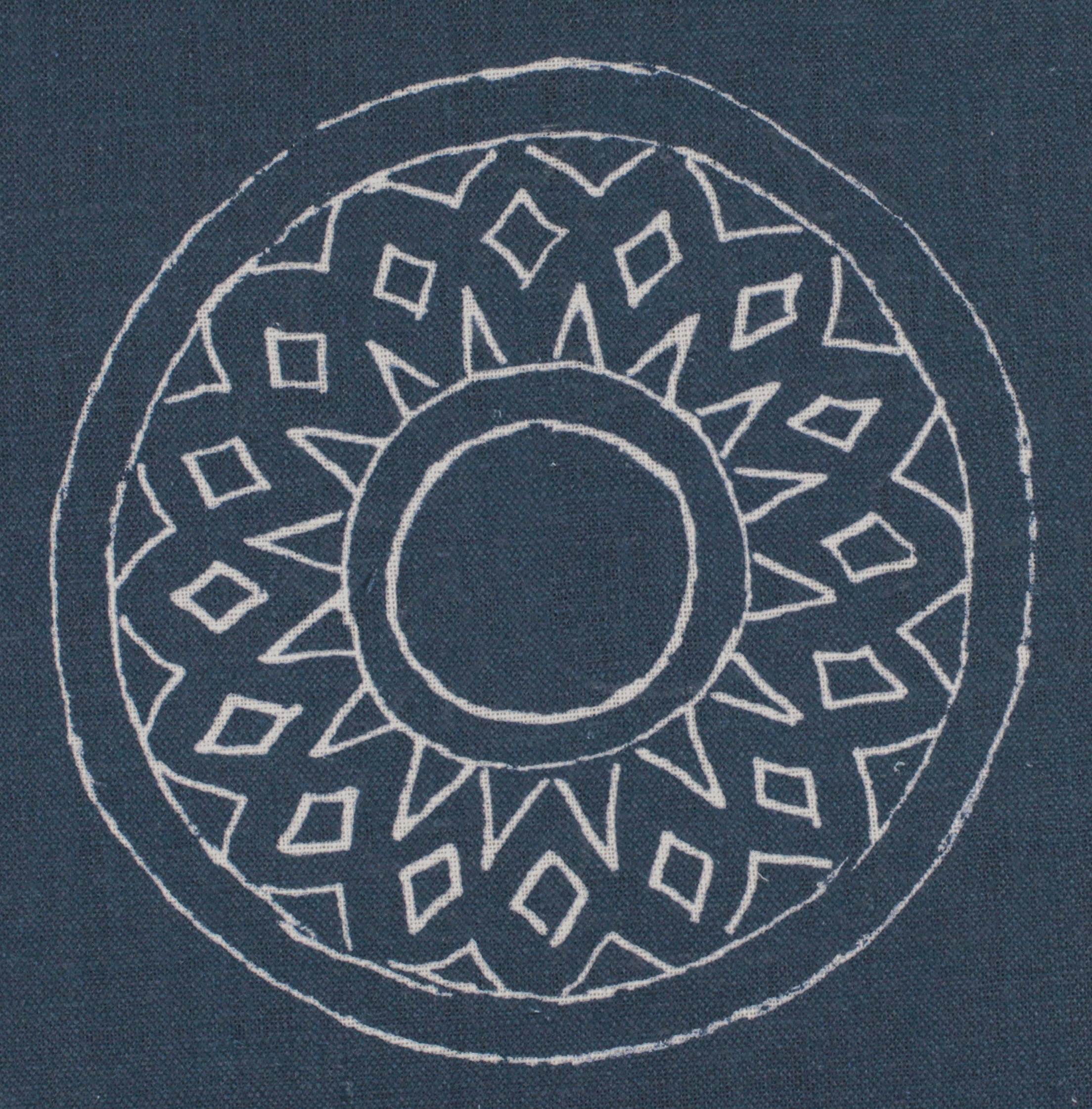 Detail of fabric in a repeating circular geometric print in light gray on a navy field.