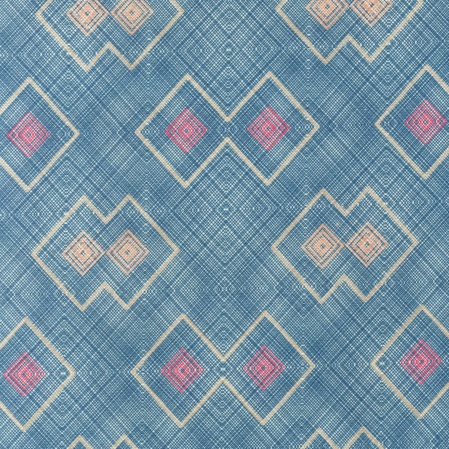 Detail of fabric in a detailed diamond lattice print in shades of red and orange on a blue field.