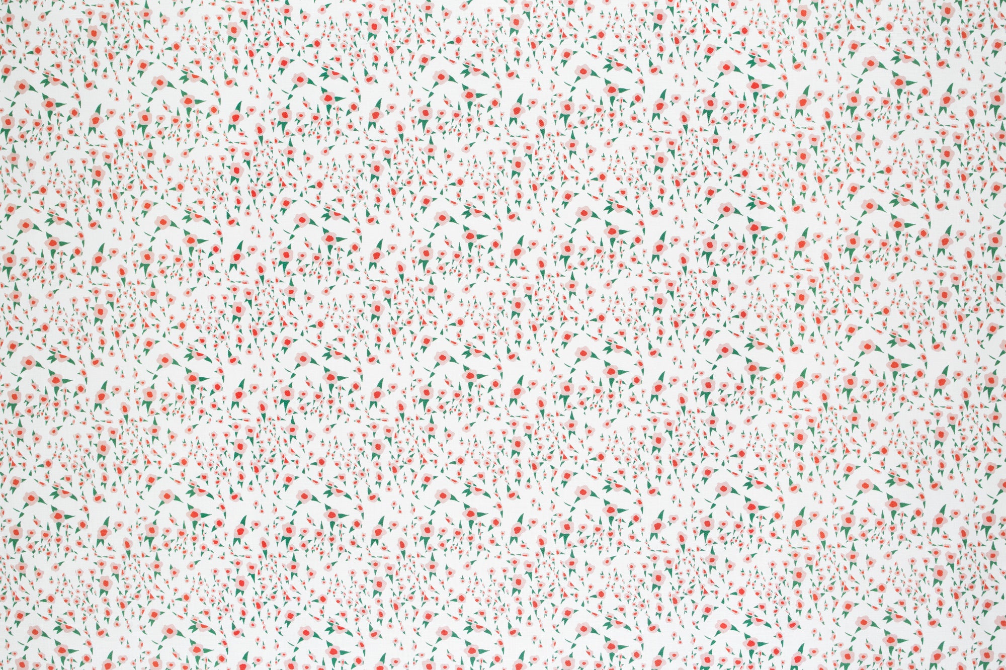 Detail of fabric in a small-scale floral pattern in pink, red and green on a cream field.