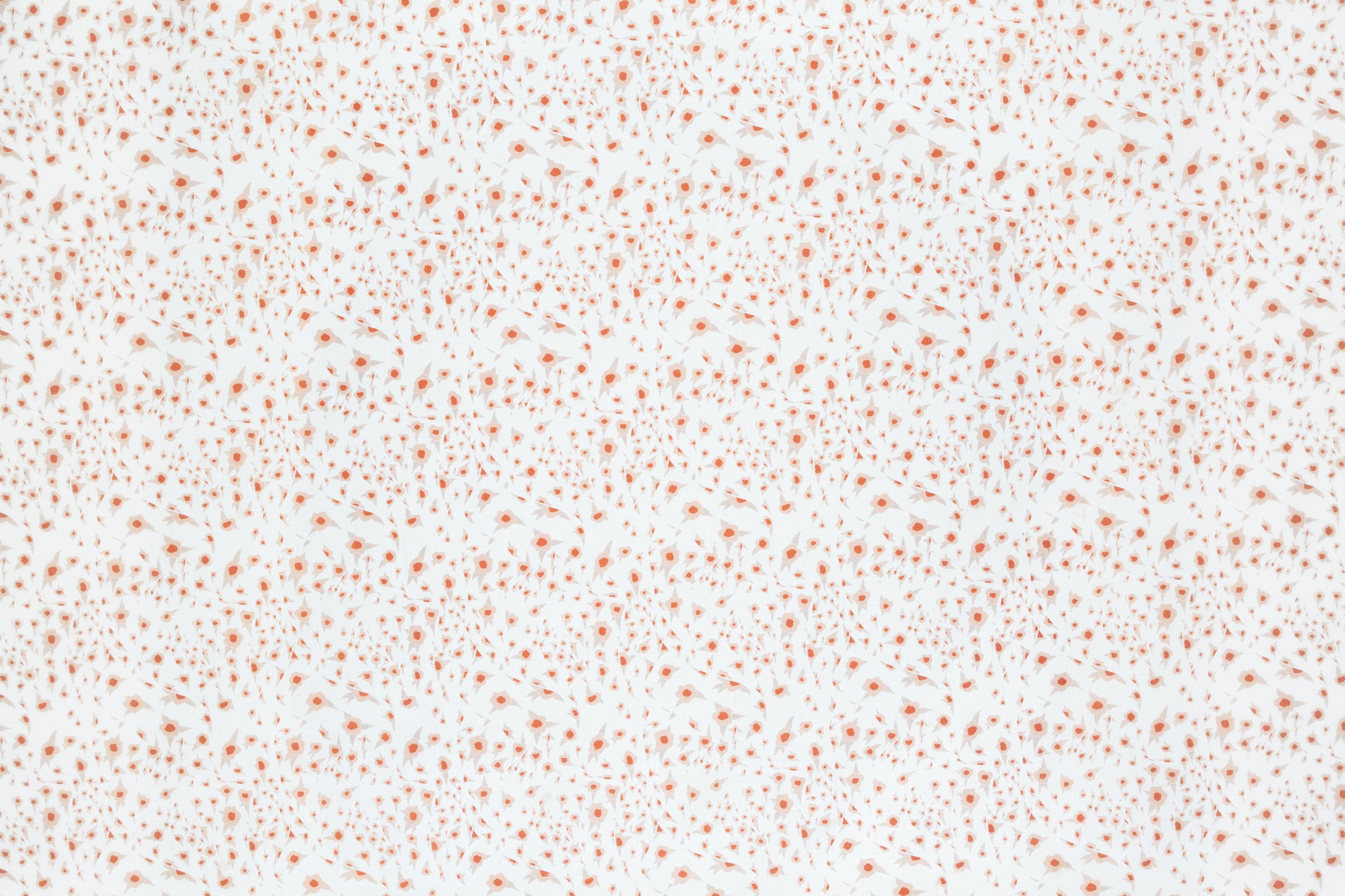 Detail of fabric in a small-scale floral pattern in pink and coral on a cream field.
