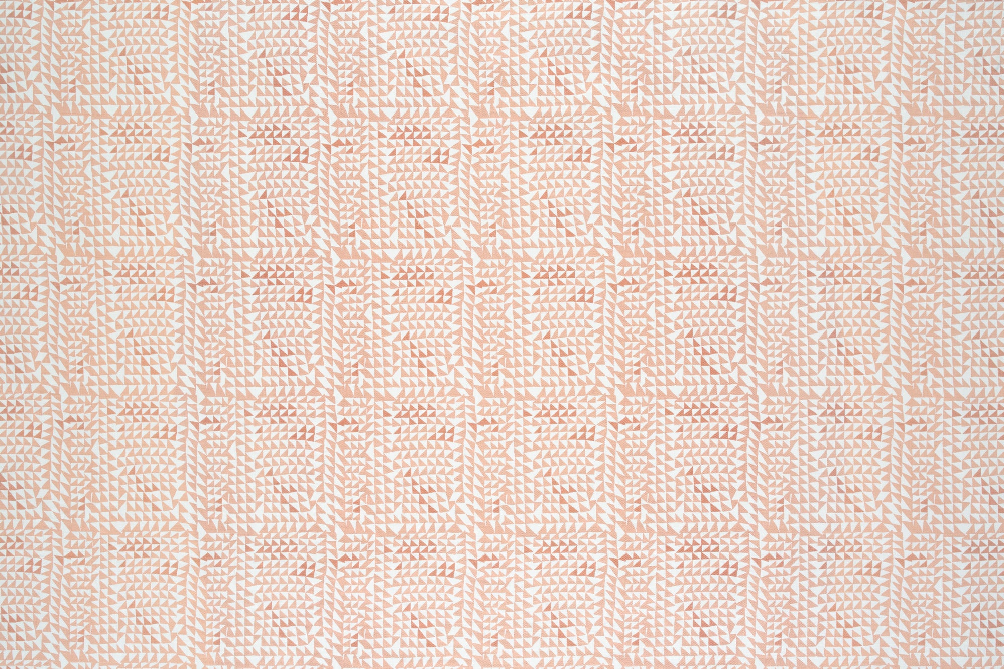 Detail of fabric in a dense triangle grid print in shades of pink and coral on a white field.