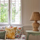 A cozy living room tableau with a couch upholstered in a playful rainbow floral print on a white field.