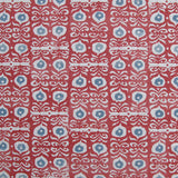 Fabric in a repeating damask print in white and blue on a red field.