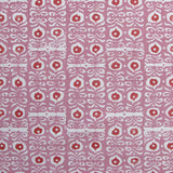 Fabric in a repeating damask print in white and red on a pink field.