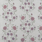 Detail of fabric in a floral lattice print in pink, purple and green on a tan field.