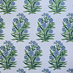 Detail of fabric in a repeating floral print in shades of blue and green on a light blue field.