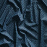 Close up of gently draped printed linen with dense floral medallion pattern in tonal dark blue.