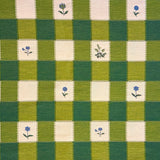 Green and cream checkered fabric with small floral patterns in selected squared