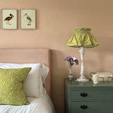 A cozy bedroom tableau with a amp and throw pillows all upholstered in the same scrolling stem and leaf print.