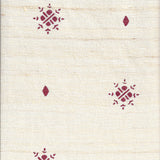 Detail of fabric in a repeating geometric starburst print in red on a cream field.