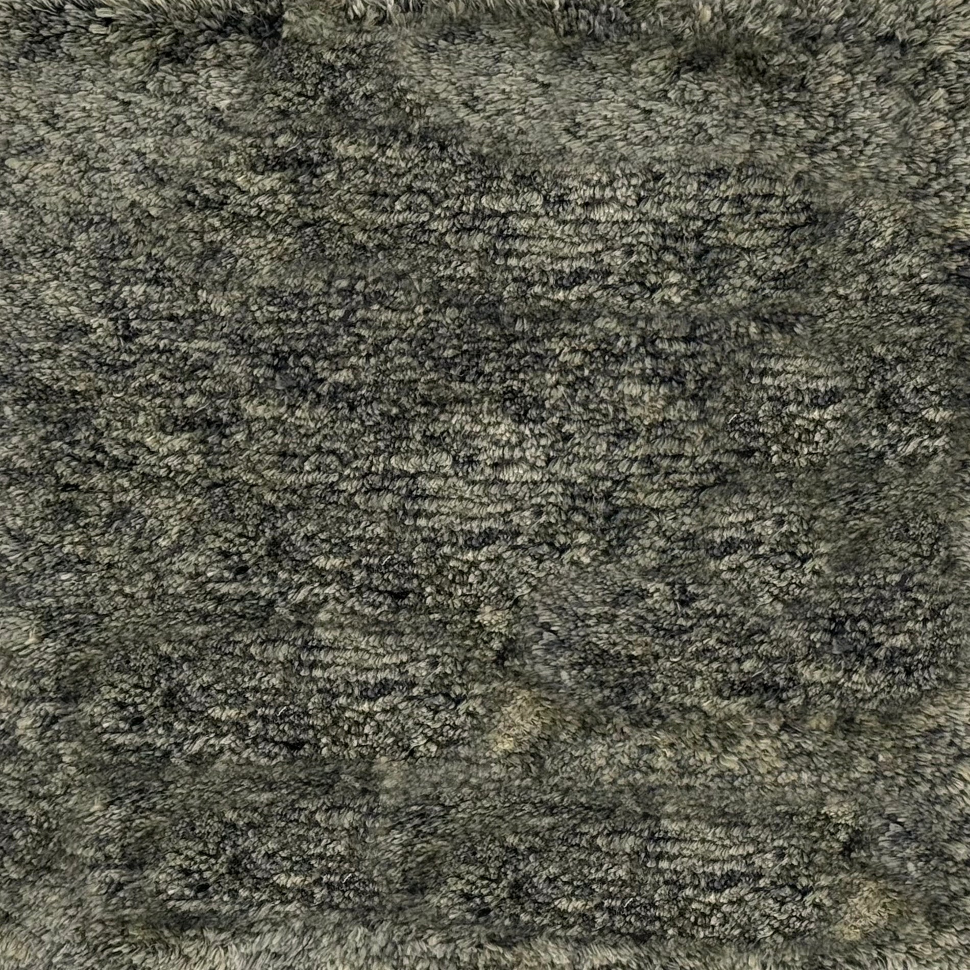 A close-up texture shot of a shaggy silk  high-pile rug in a mottled gray.