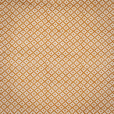 Detail of fabric in a diamond lattice print in orange on a cream field.