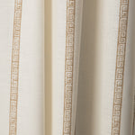 Draped printed fabric in a minimal geometric linear pattern in gold on a cream field.