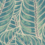 Detail of fabric in a large-scale leaf print in shades of blue and turquoise on a tan field.