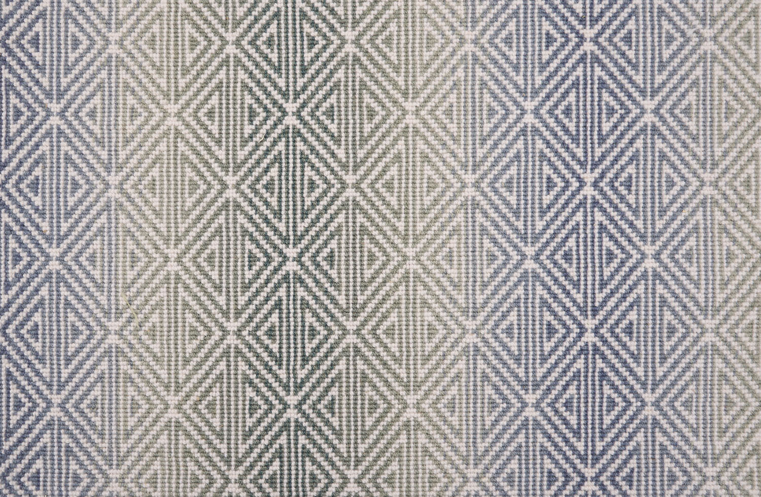 Broadloom carpet with triangle pattern with an ombré background in blue and green. 
