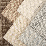 Stack of broadloom carpet samples in a textural design in a range of neutrals randing from ivory, to grey to brown.