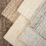 Stack of broadloom carpet samples in a textural design in a range of neutrals randing from ivory, to grey to brown.