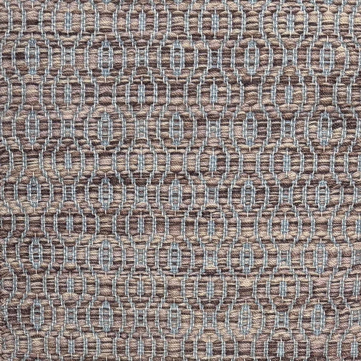 Handwoven wool rug with undulating oval stripe in shades of brown on an grey-blue field. 