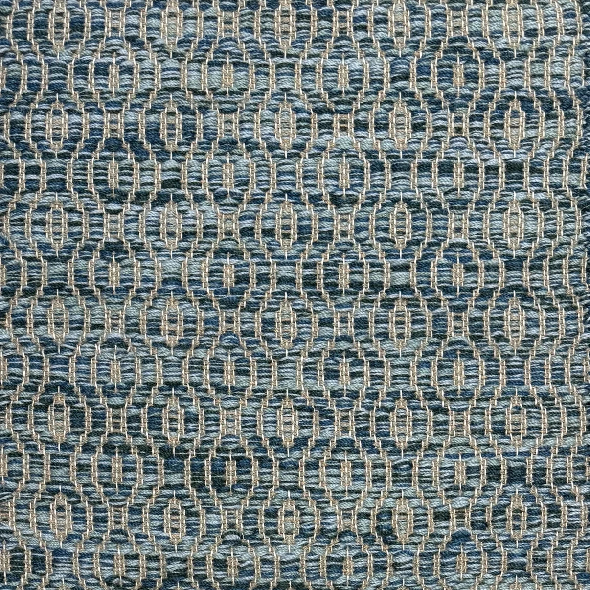 Handwoven wool rug with undulating oval stripe in shades of blue on a grey field. 