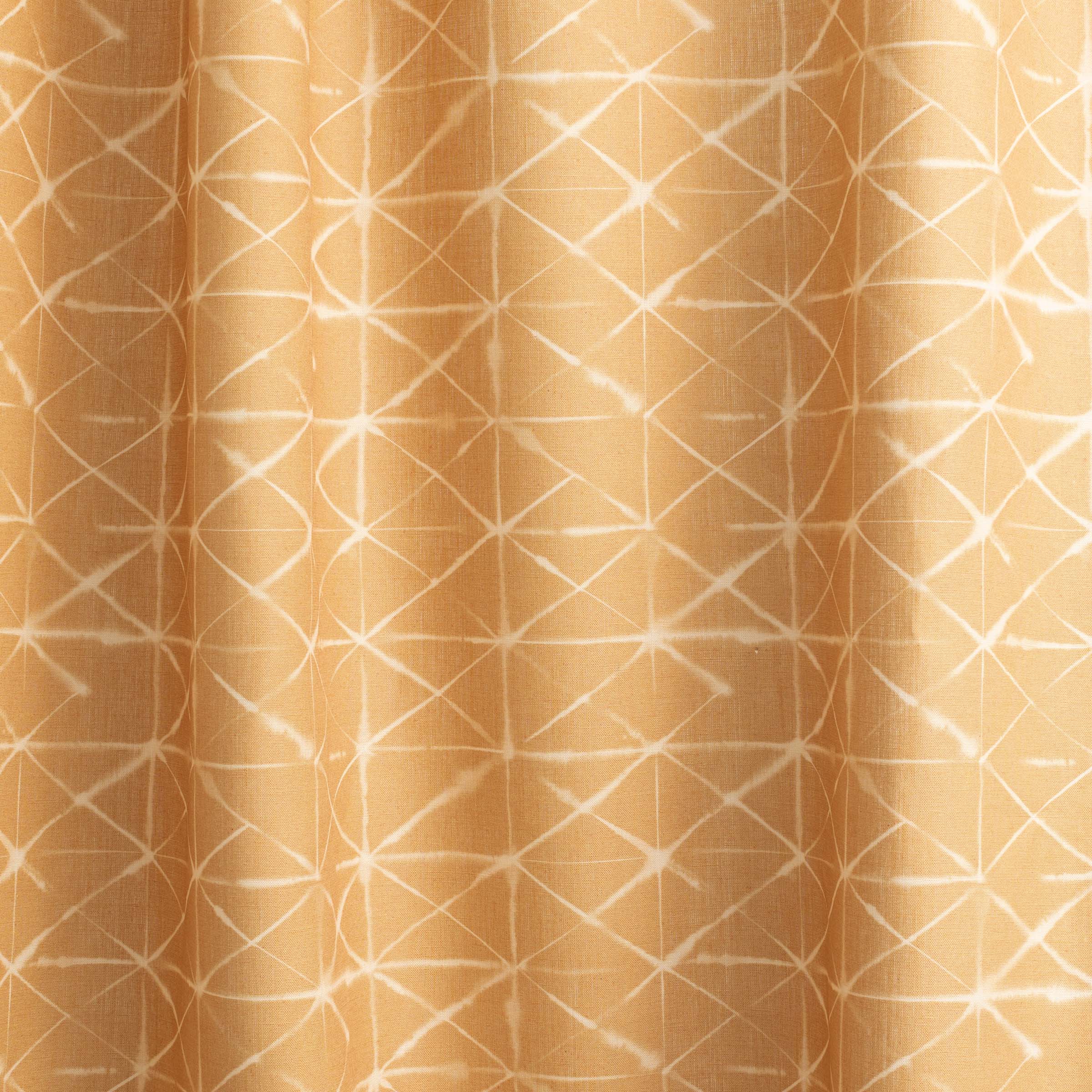 Draped fabric in a mottled lattice print in white on a burnt orange field.
