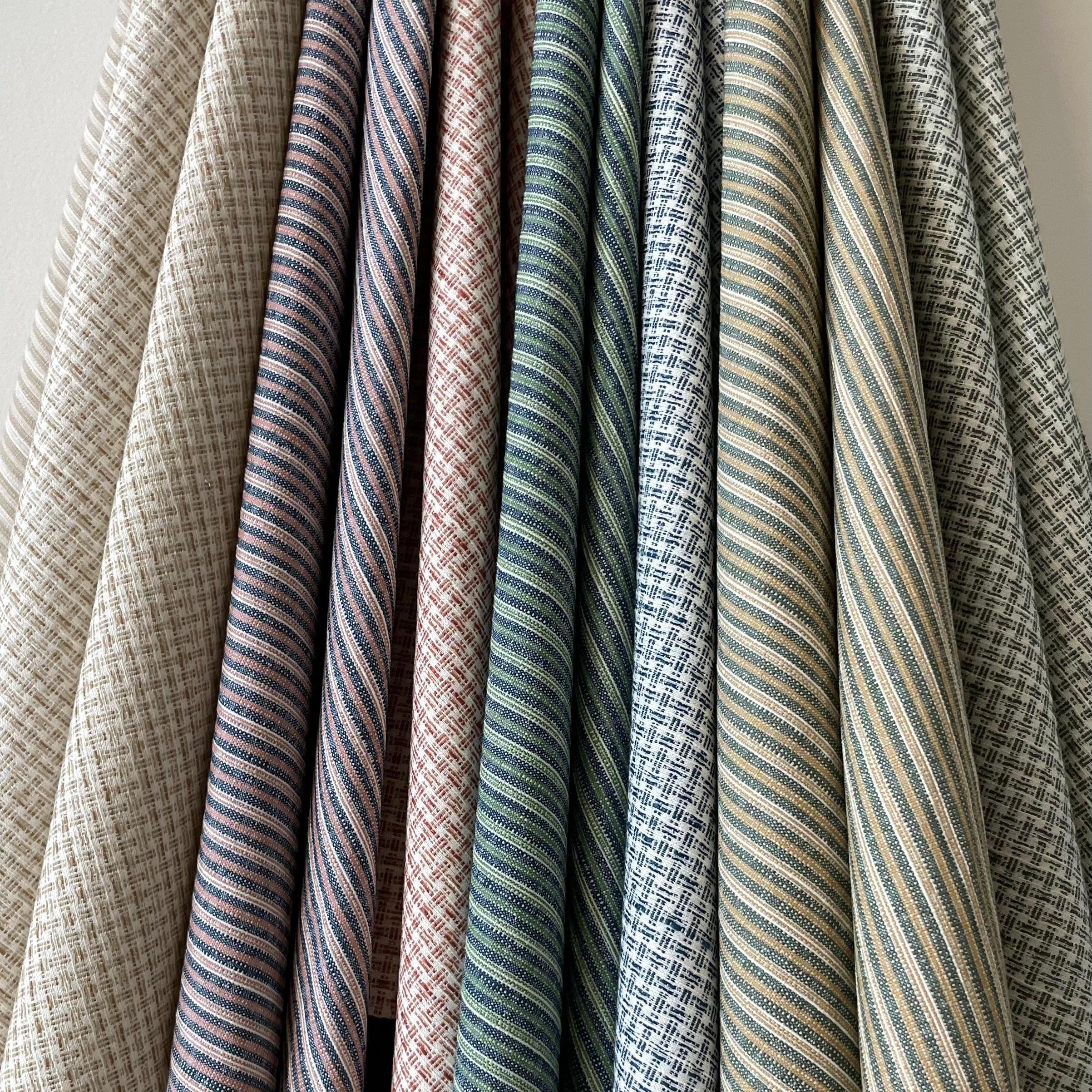 Set of hanging fabric swatches in stripe and plaid designs in various colors. 