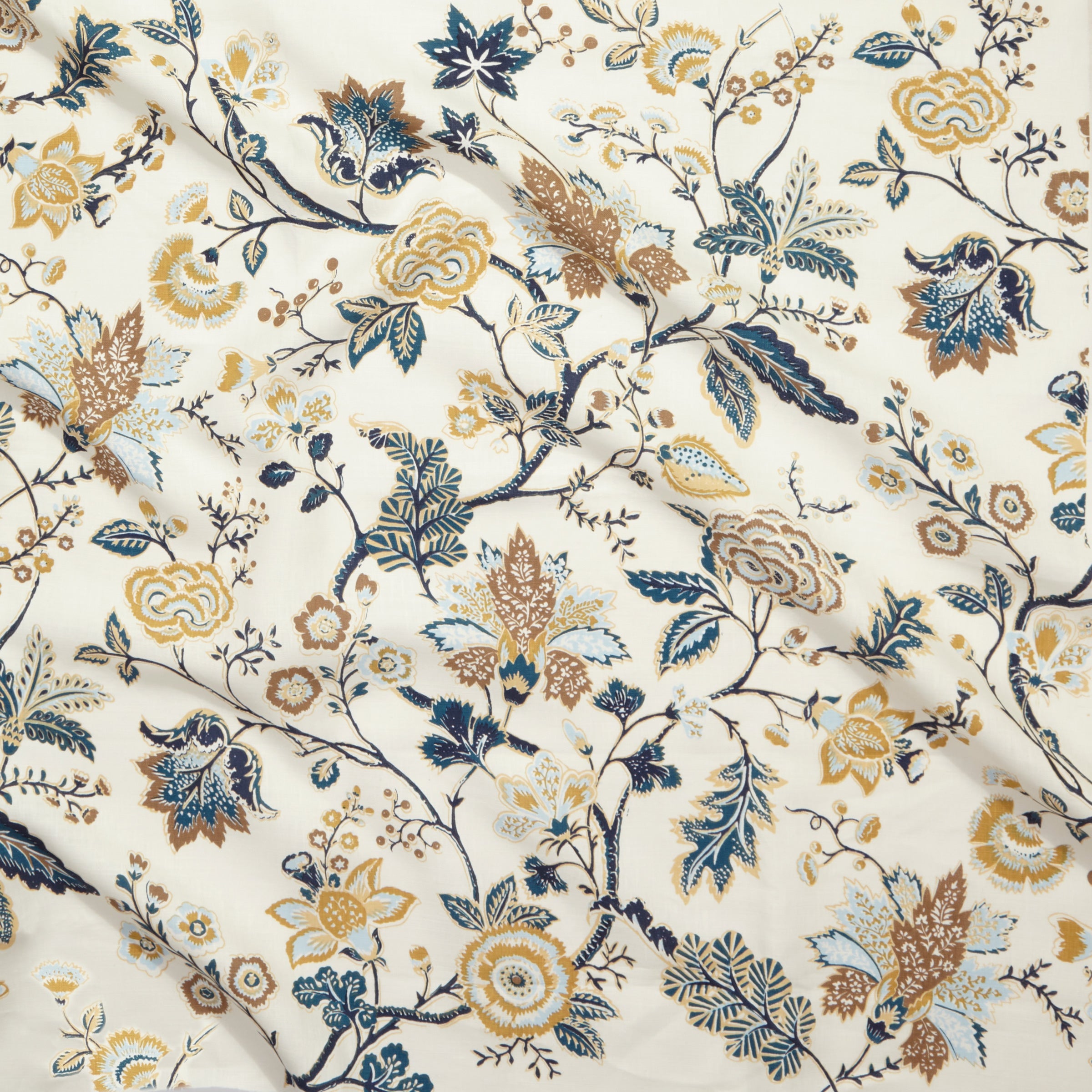 Close up of gently draped printed fabric in scrolling floral vine pattern in tan, taupe and shades of blue on cream. 