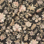 Close up of gently draped printed fabric in scrolling floral vine pattern in dark purple, blush pink, tan and brown on black.