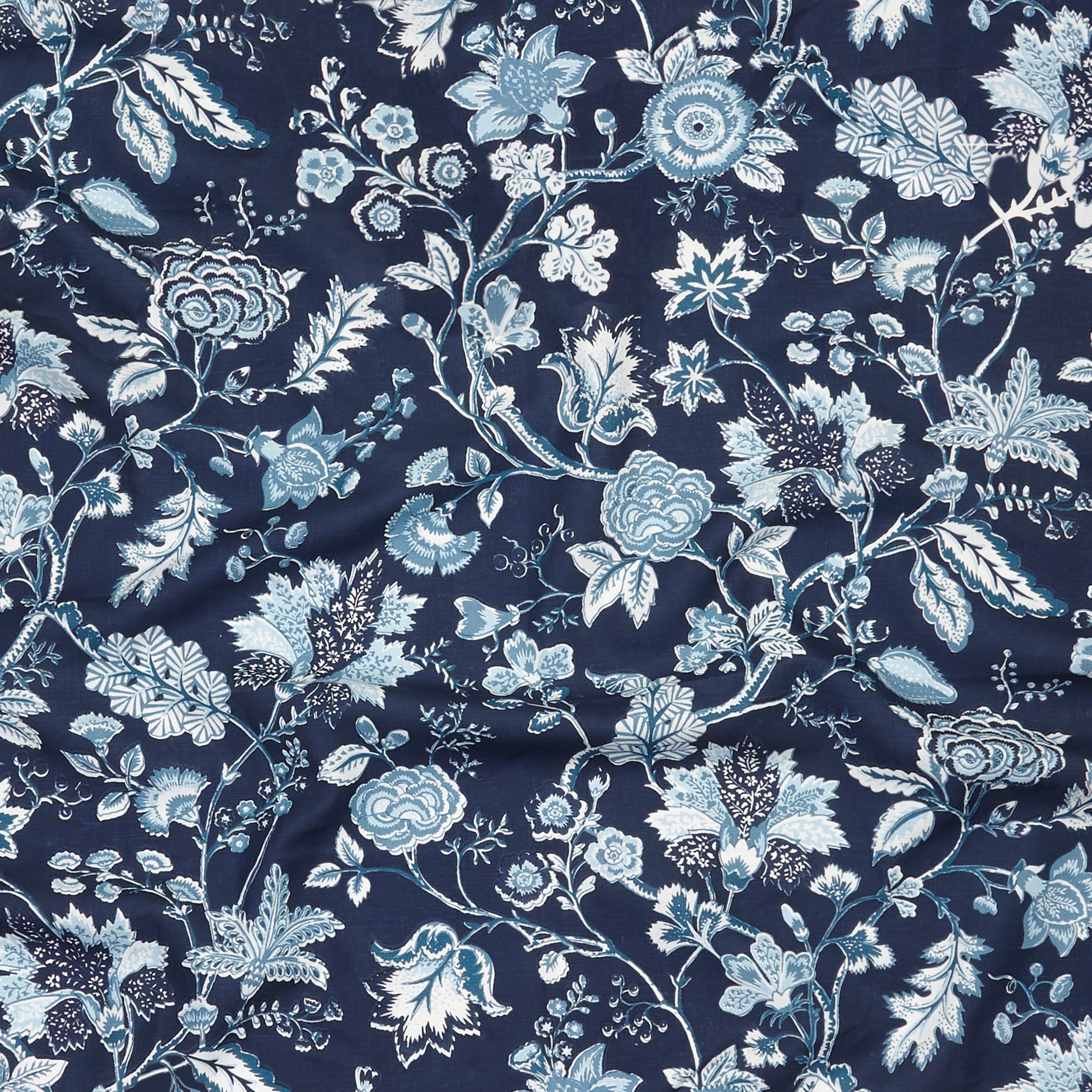 Close up of gently draped printed fabric in scrolling floral vine pattern in shades of blue and white on navy blue.