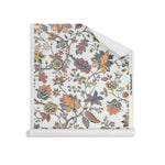 Roll of wallpaper in scrolling floral vine pattern in yellow, clay pink, orange, navy blue and olive green on white. 
