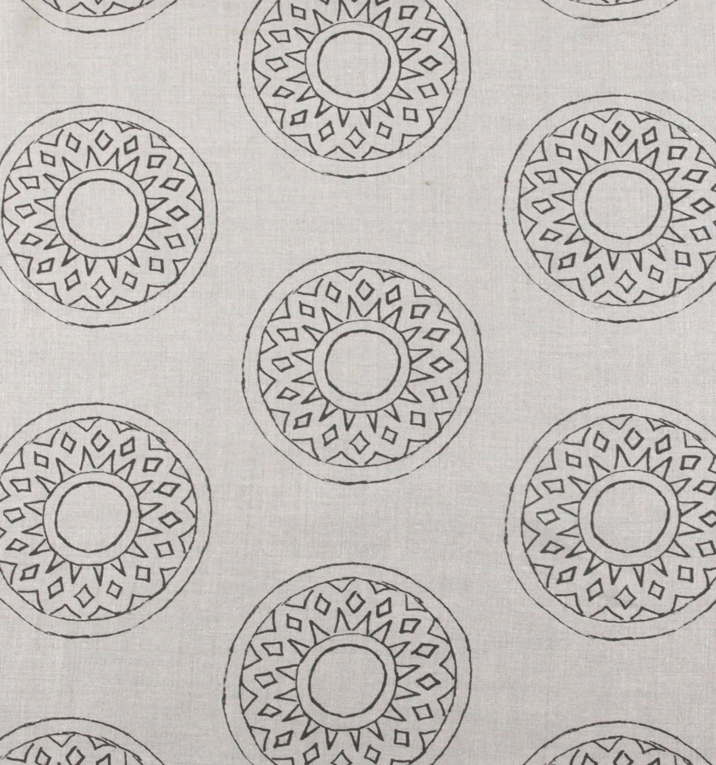 Detail of fabric in a repeating circular geometric print in gray on a greige field.