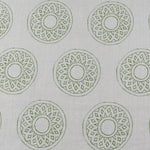 Detail of fabric in a repeating circular geometric print in green on a greige field.