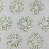 Detail of fabric in a repeating circular geometric print in green on a greige field.