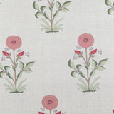 Detail of fabric in a large-scale marigold print in coral, red and green on a white field.