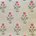 Detail of fabric in a large-scale marigold print in pink, red and green on a cream field.