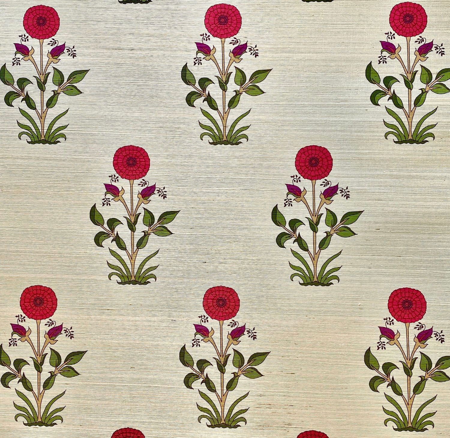 Detail of fabric in a large-scale marigold print in red, purple and green on a cream field.