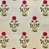 Detail of fabric in a large-scale marigold print in red, purple and green on a cream field.