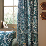 Green leaf-patterned curtain in a room with a couch and decorative items.